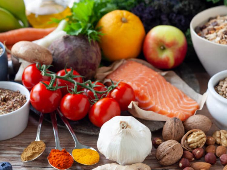 Auf diesem Bild sind viele gesunde Nahrungsmittel zu sehen, darunter Lachs, Tomaten, Kräuter, Nüsse