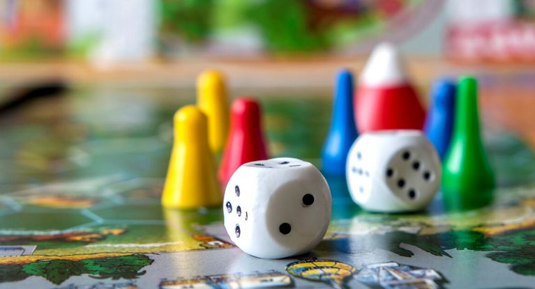 Spielen und Lesen Spielfiguren und Würfel auf einem Spielbrett