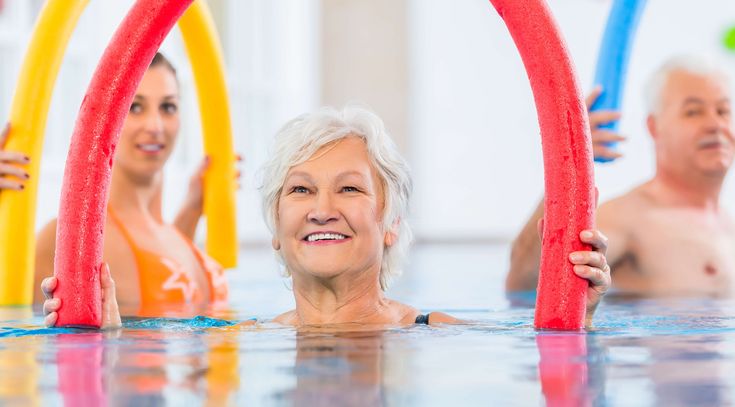 Patientinnen üben mit Poolnudeln im Wasser